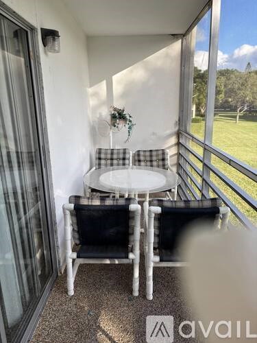 A balcony with a table and chairs overlooking a green field.