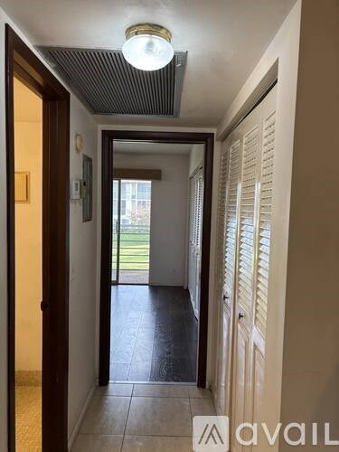 A hallway with a light on the ceiling and a door on the left.