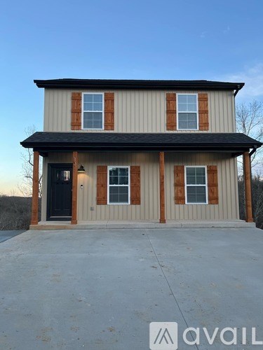 A two-story house with a black door and windows with brown trim.