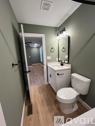 A bathroom with a toilet, sink, and mirror.