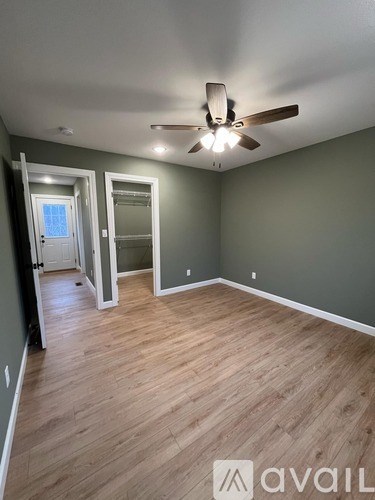 A room with a ceiling fan and wooden flooring.