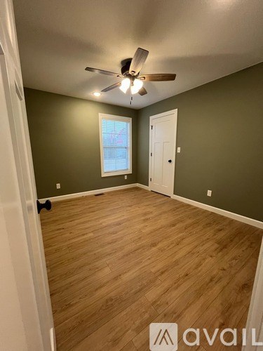A room with a ceiling fan and wooden flooring.