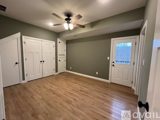 A room with a ceiling fan and wooden flooring.