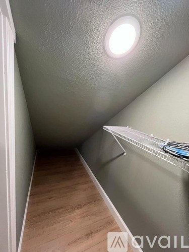 A narrow hallway with a light on the ceiling and a shelf on the wall.