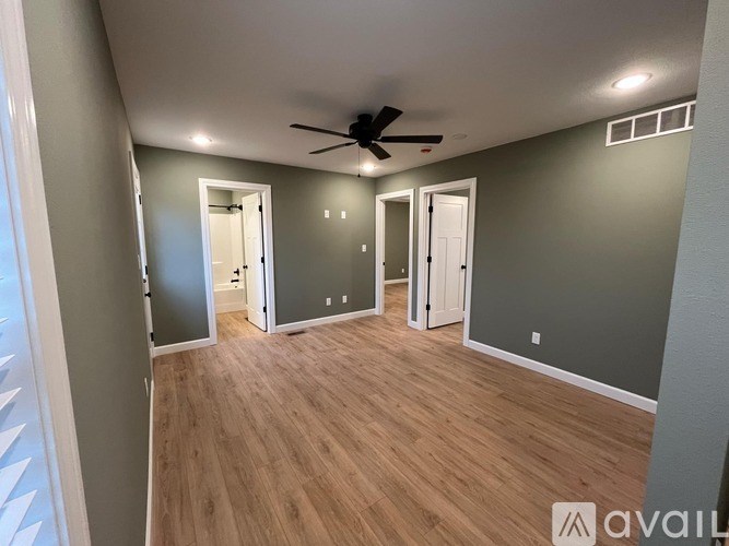 A room with a ceiling fan and wooden flooring.