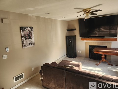 A living room with a brown couch and a flat screen TV mounted above a fireplace.