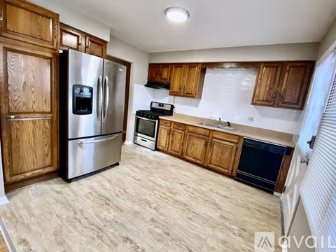 A kitchen with wooden cabinets and a stainless steel refrigerator.
