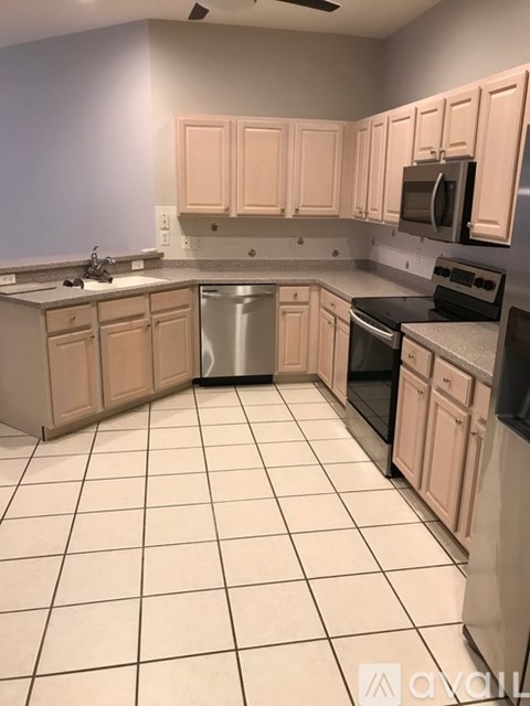 A kitchen with white tiles and wooden cabinets.