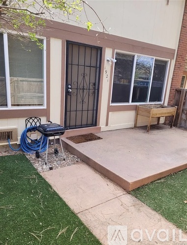 A patio with a bench and a table is in front of a house.