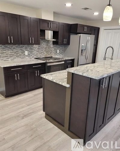 A kitchen with dark brown cabinets and a marble countertop.
