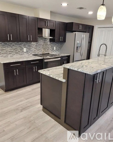A kitchen with dark brown cabinets and a marble countertop.