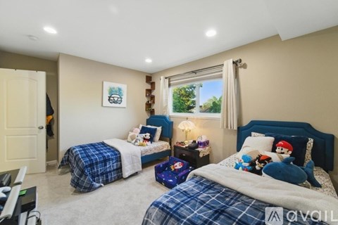 A bedroom with two beds and a window with curtains.