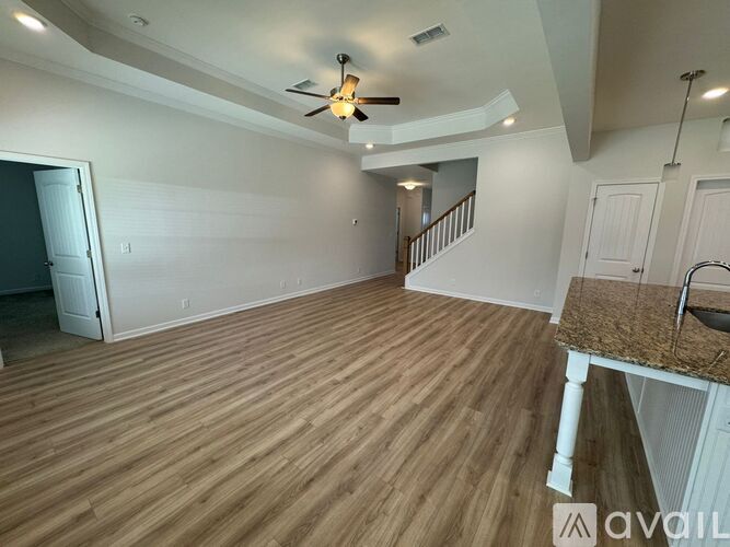 A spacious room with wooden flooring and a ceiling fan.