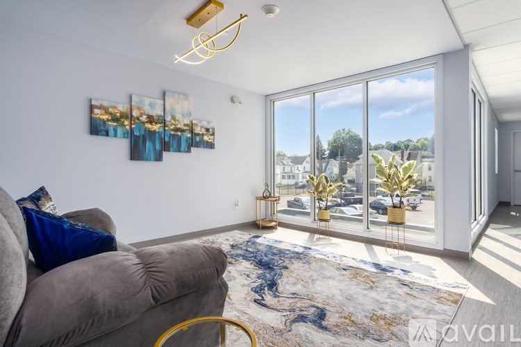 A living room with a grey couch and a large window.
