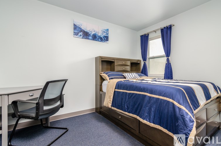 A bedroom with a bed, desk, and chair.