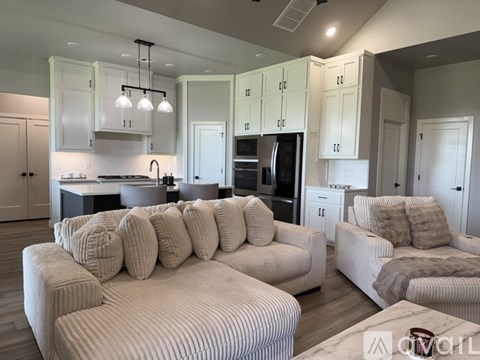 A modern living room with a large sectional sofa and a kitchen area in the background.