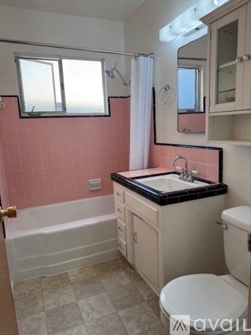 A bathroom with pink tiles and a white bathtub.