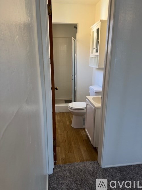A bathroom with a toilet, sink and mirror.