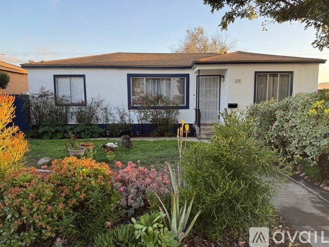 A white house with a garden in front.