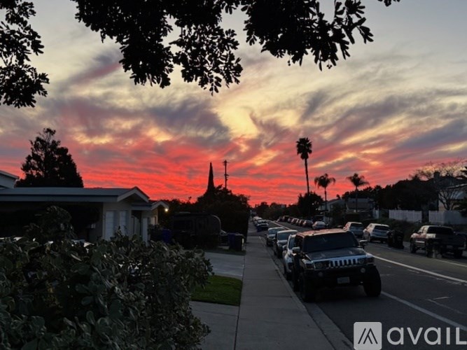 A street with cars parked on the side and houses on the other side.