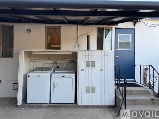 A white garage with a blue door and a washer and dryer in it.