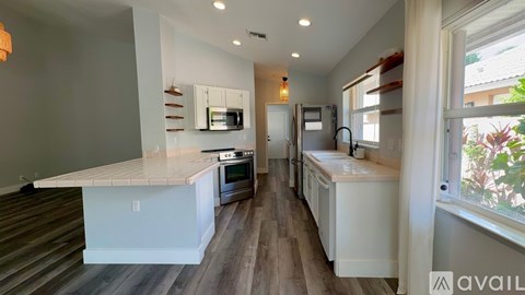 A kitchen with white cabinets and a wooden floor.