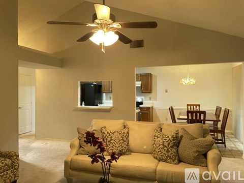 A living room with a beige couch and a ceiling fan.