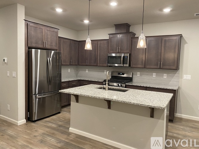 A kitchen with a refrigerator, microwave, and oven.