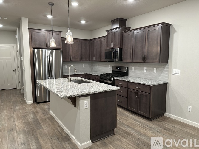 A kitchen with a granite countertop and dark wood cabinets.