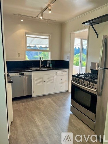 A kitchen with a stove, sink, and cabinets.