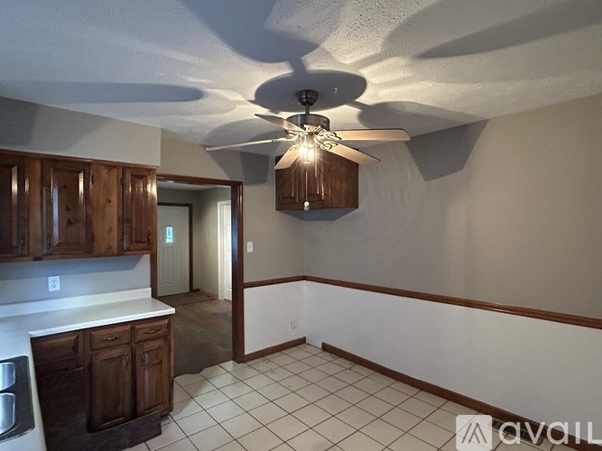 A kitchen with a ceiling fan and wooden cabinets.