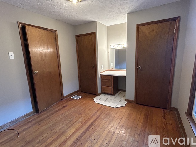 A room with wooden floors and three doors.