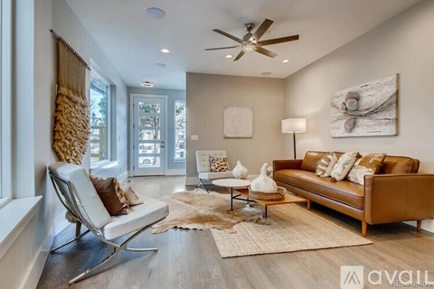 A living room with a brown leather couch and a white chair.