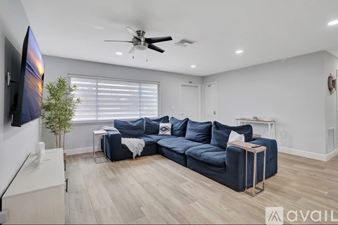 A living room with a blue couch and a television on the wall.