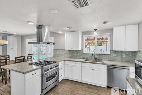 A modern kitchen with white cabinets and a stainless steel stove top.