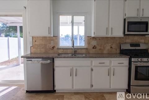 A kitchen with white cabinets and a granite countertop.
