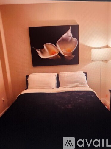 A bedroom with a large bed and a painting of two shells above it.