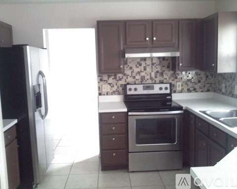 A kitchen with brown cabinets and a black and white tiled backsplash.