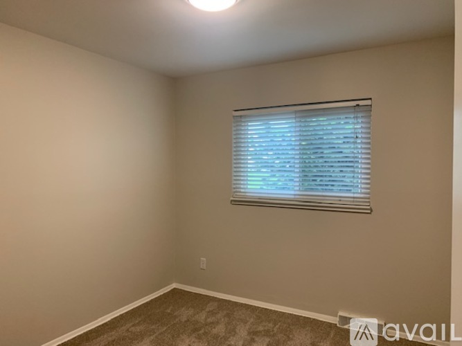 A room with a window covered by blinds and a carpet on the floor.