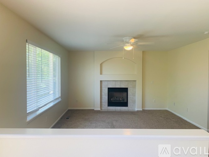 A living room with a fireplace and a fan on the ceiling.