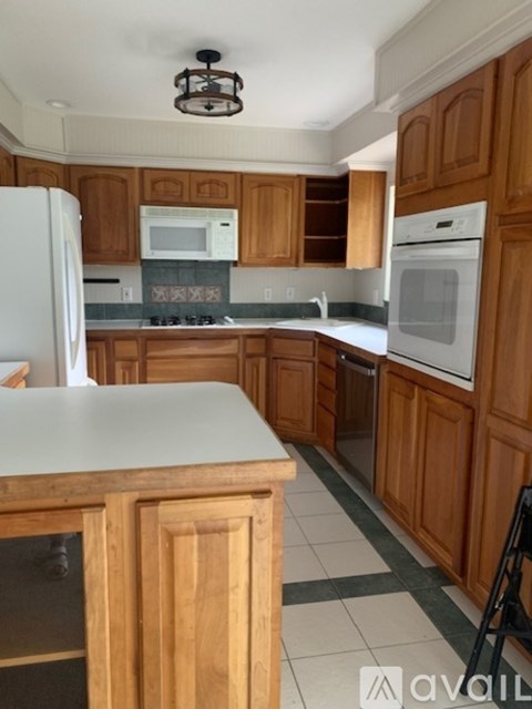 A kitchen with wooden cabinets and a white counter.