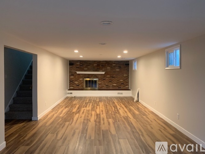 A spacious room with wooden flooring and a brick fireplace.