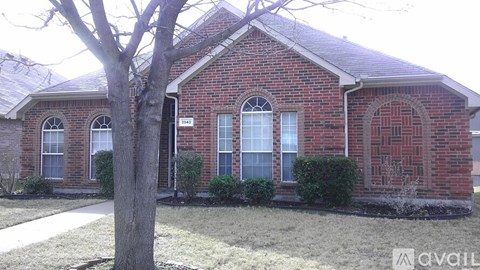 A red brick house with a tree in front.