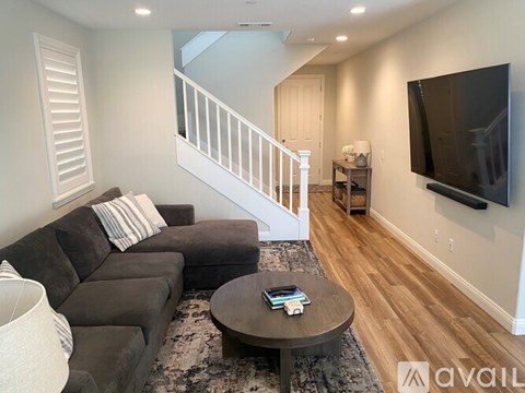 A living room with a grey couch and a television on the wall.