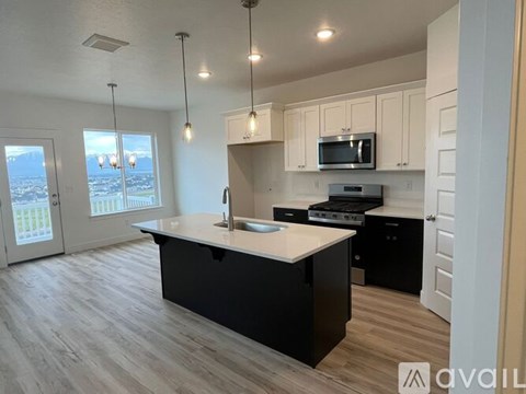 A kitchen with a large island and a view of the outdoors through the windows.