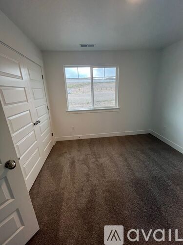 A room with a carpeted floor and a window showing a beach view.