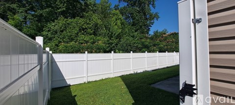 A white fence with a gate is in the foreground of a grassy area.