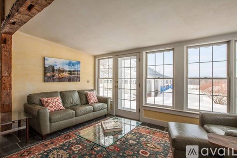 A living room with a couch, a coffee table, and a painting on the wall.