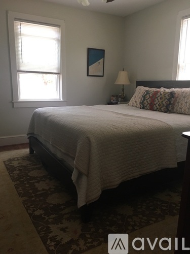 A bedroom with a large bed and a rug on the floor.