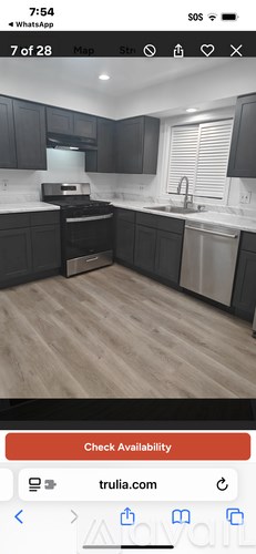 A kitchen with black cabinets and a wooden floor.